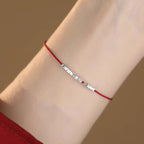 Small silver nugget on a red cord