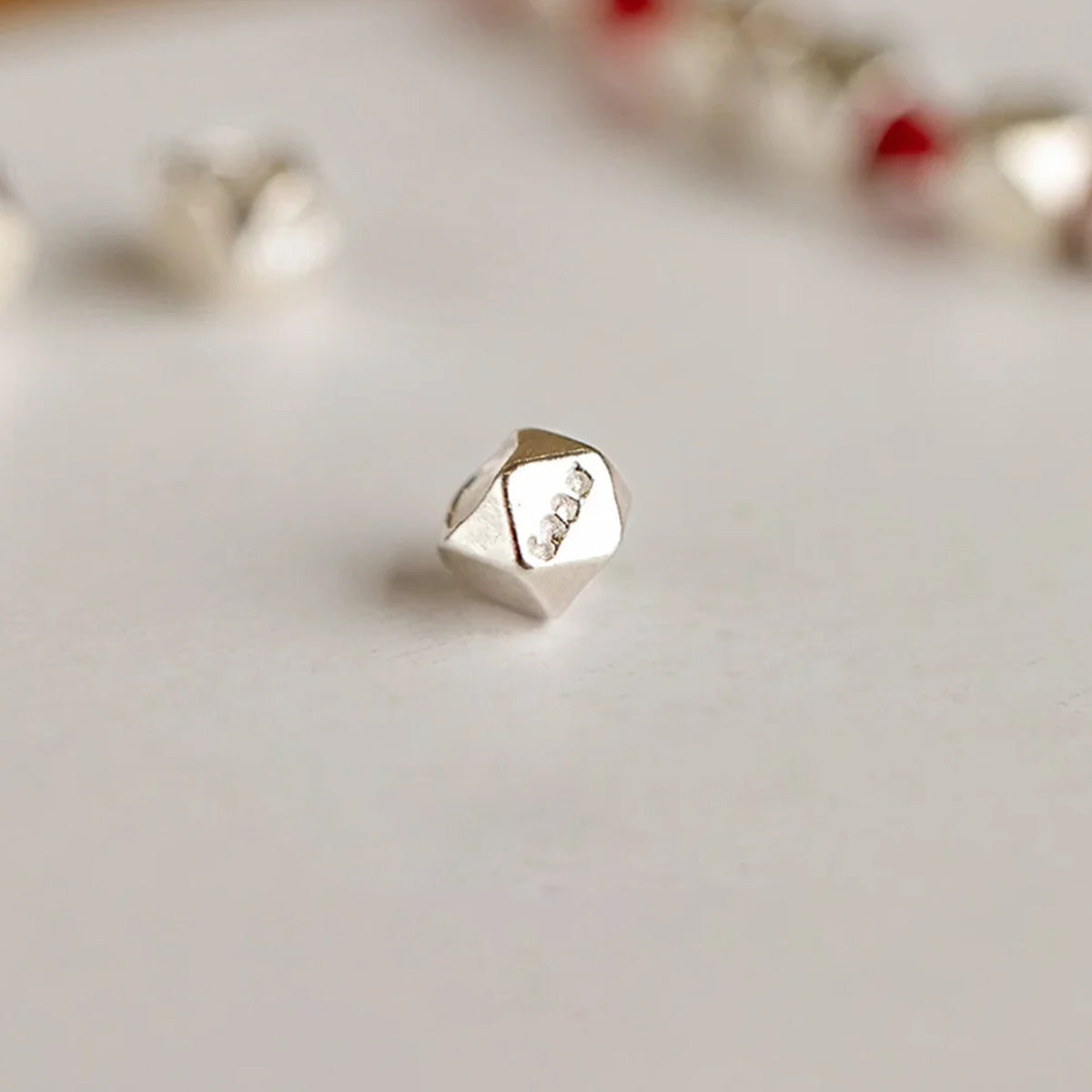 Small silver nugget on a red cord