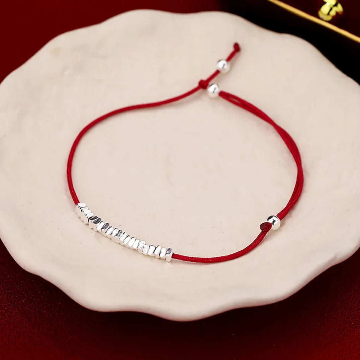 Small silver nugget on a red cord