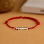 Small silver nugget on a red cord