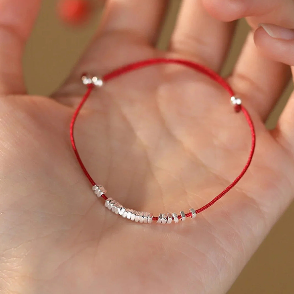 Small silver nugget on a red cord