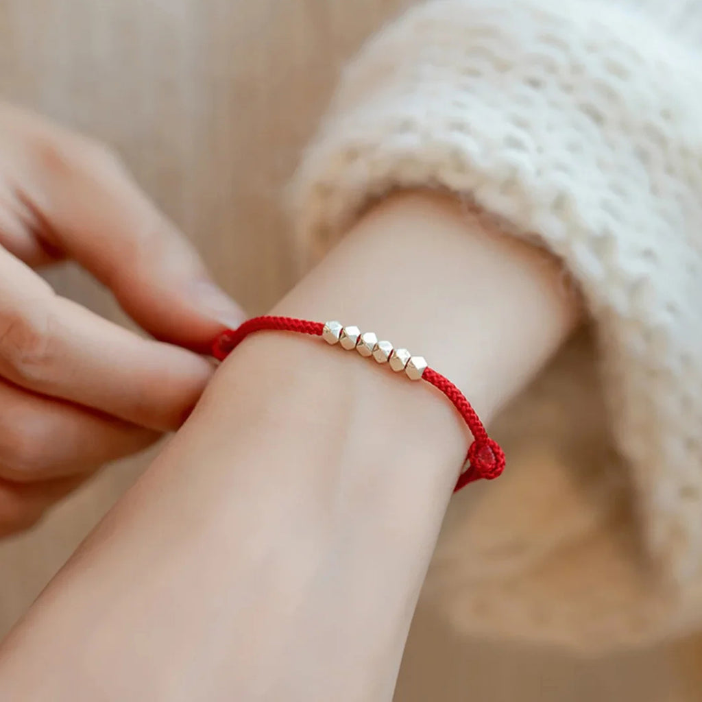Small silver nugget on a red cord
