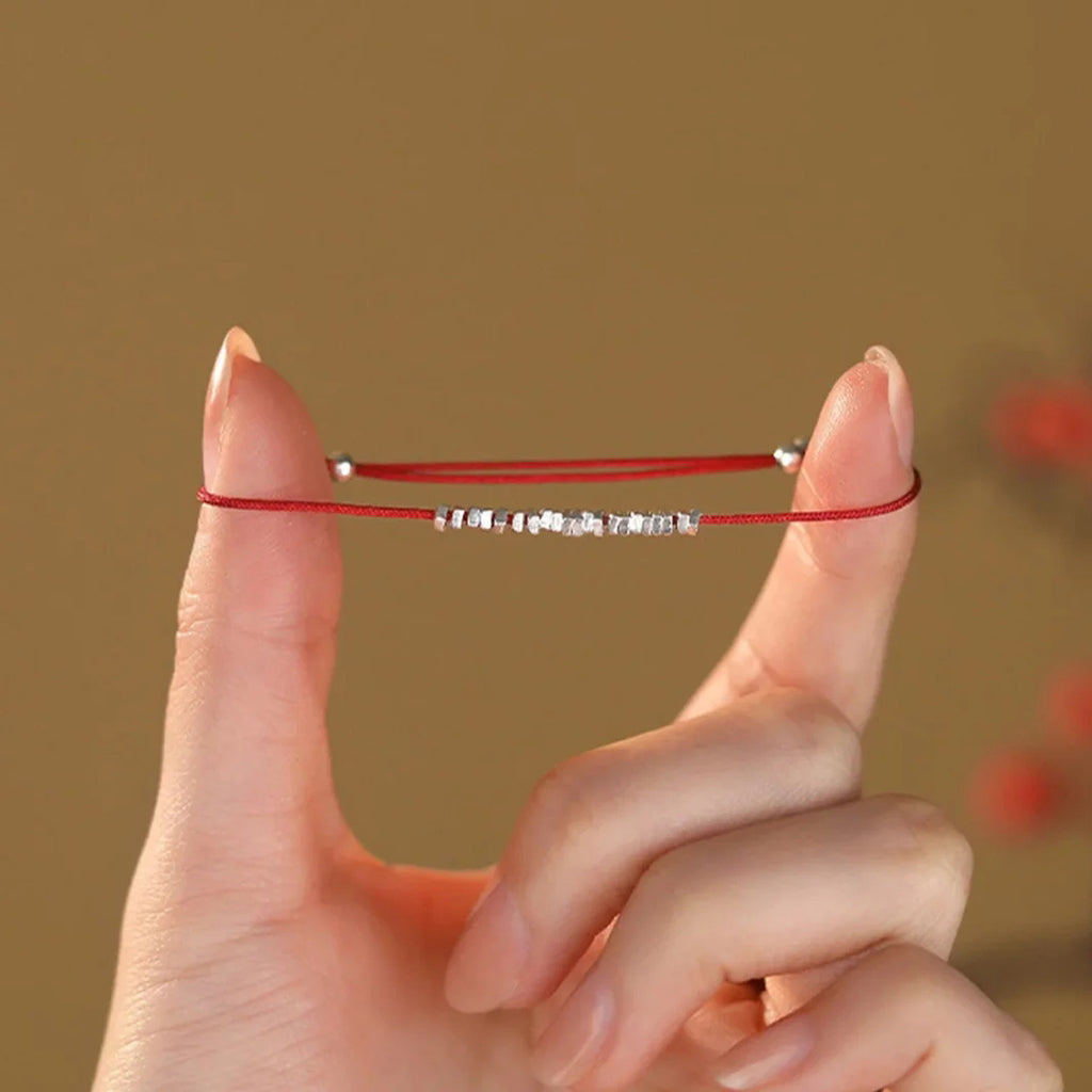 Small silver nugget on a red cord