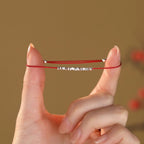 Small silver nugget on a red cord